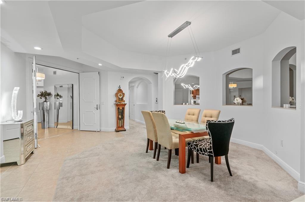 Dining space with arched walkways, recessed lighting, and light colored carpet