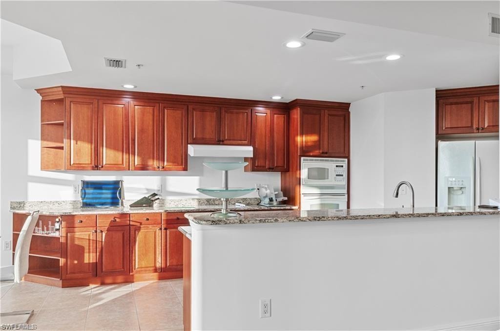 Kitchen with open shelves, light stone counters, white appliances, light tile patterned floors, and recessed lighting
