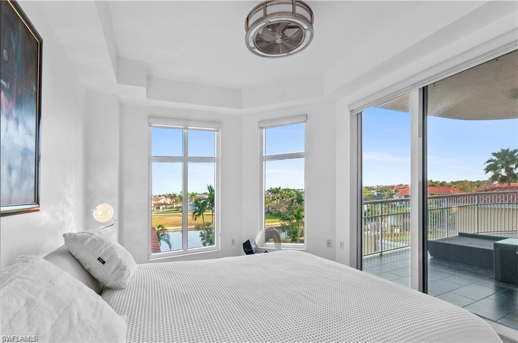 Bedroom featuring a water view, access to exterior, and a raised ceiling