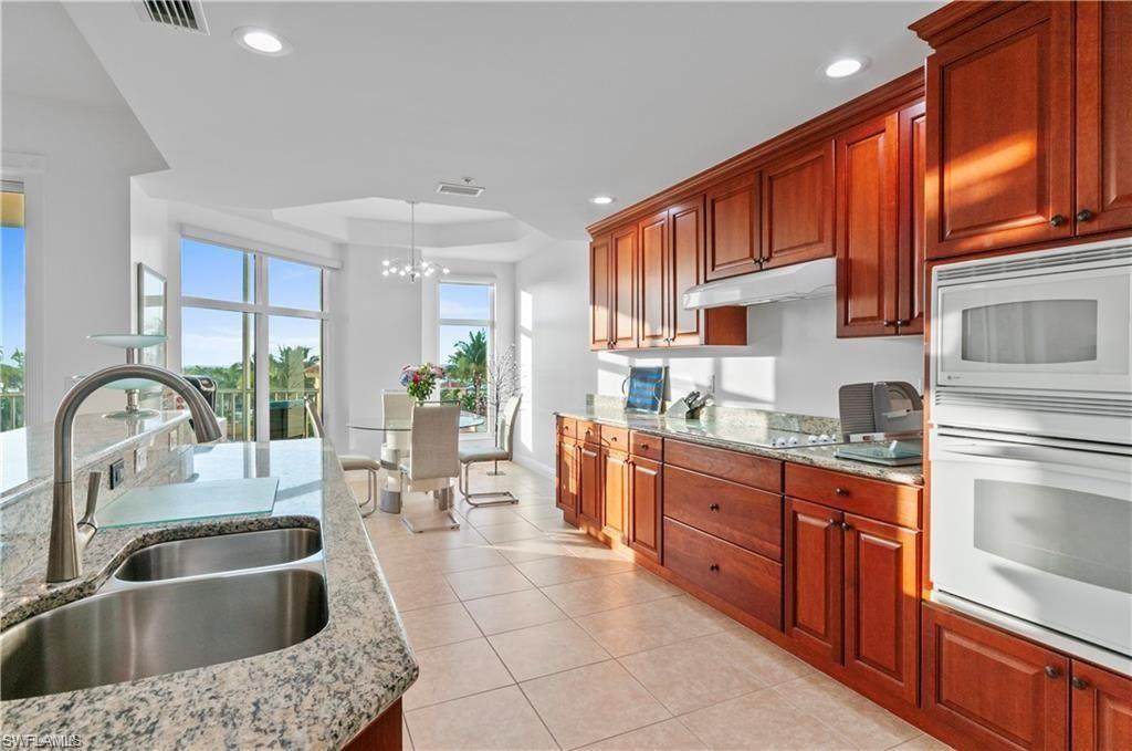Kitchen featuring light stone countertops, white appliances, pendant lighting, light tile patterned flooring, and recessed lighting