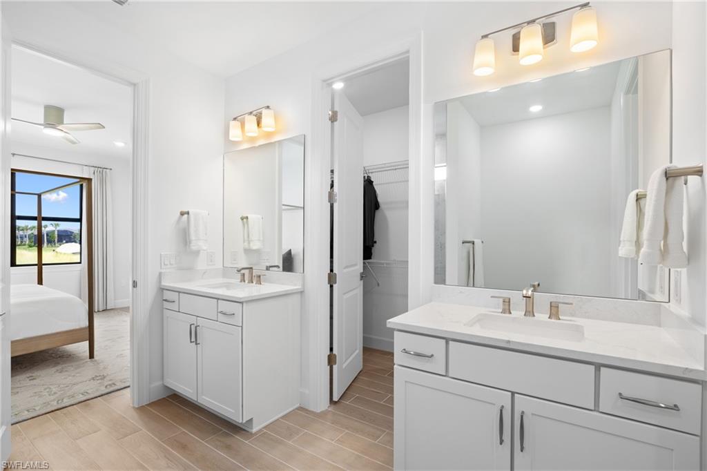 Double vanity with white cabinetry, integrated sinks, brushed nickel fixtures, and light wood-finish flooring