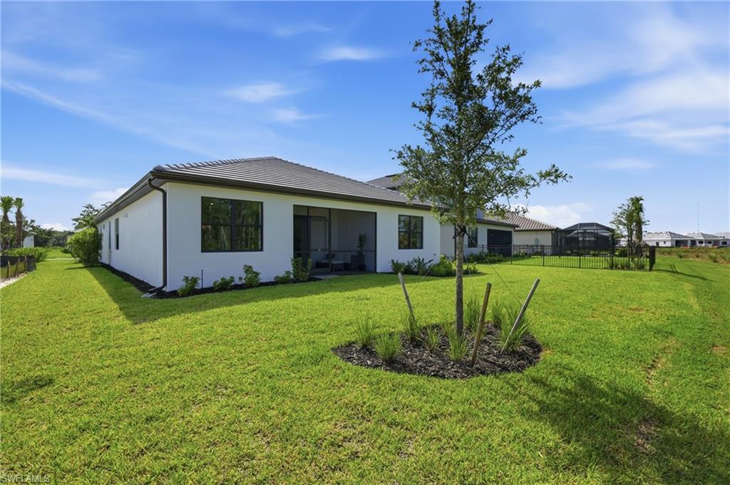 Expansive backyard featuring a manicured lawn, screened patio, and mature landscaping