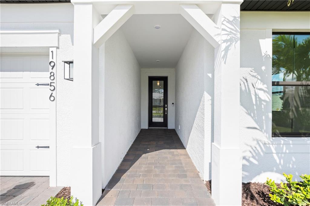 Covered entryway featuring a full-light entry door, paver walkway, and exterior lighting