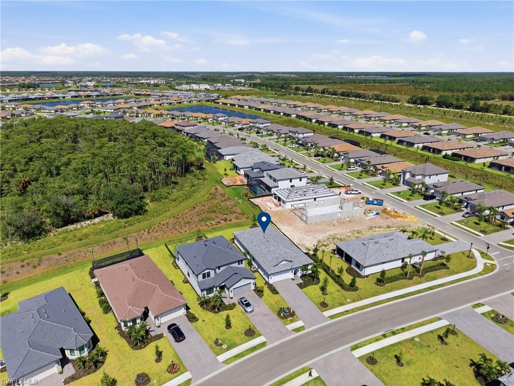 Aerial perspective showcasing the property's location within a developed community, featuring paved roadways, manicured lawns, and surrounding residential structures