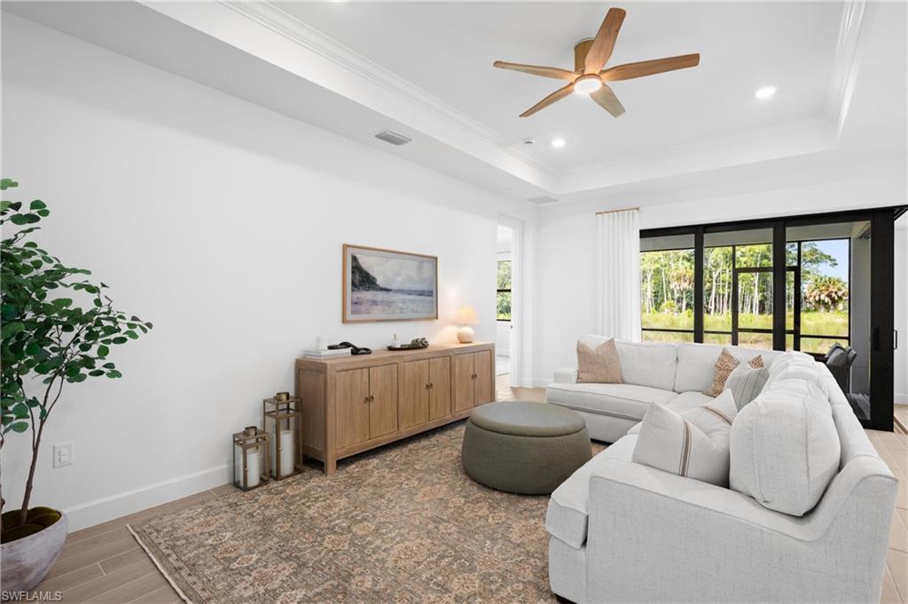 Recessed lighting, ceiling fan with wood-finish blades, tray ceiling, large sliding glass door, and wood-finish flooring