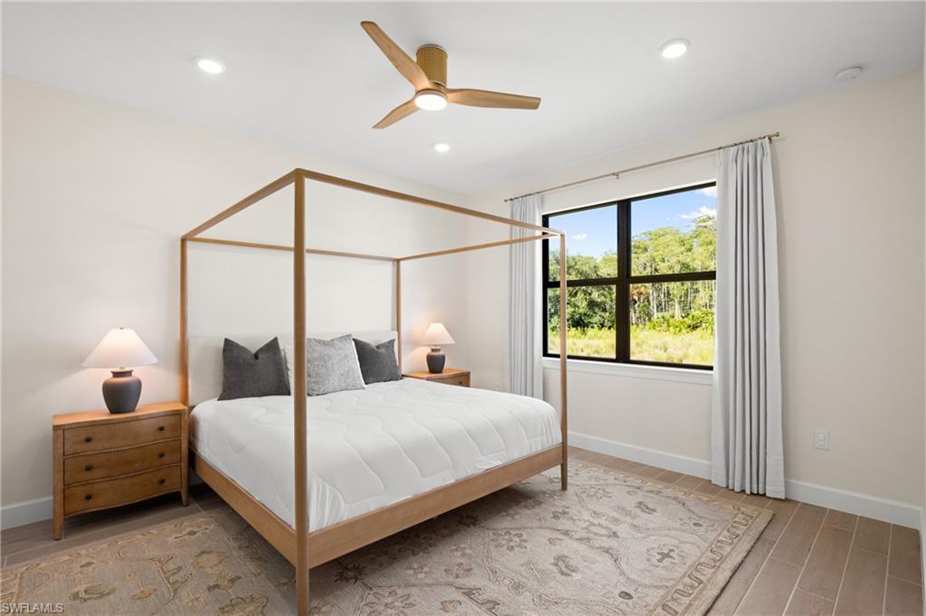 Recessed lighting, ceiling fan with wood-finish blades, large window with dark trim, wood-finish flooring, and light-toned walls