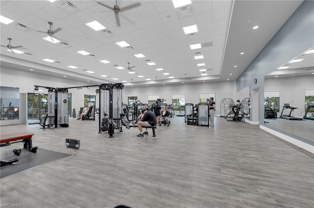 Spacious fitness center featuring modern exercise equipment, wood-finish flooring, and recessed lighting