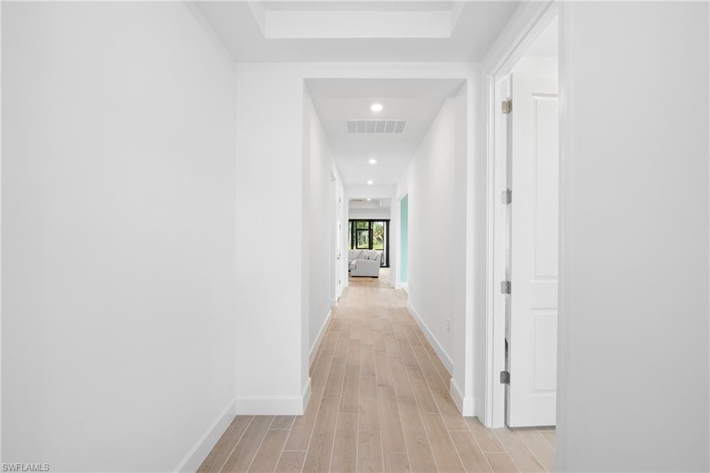 Recessed lighting illuminates the hallway with wood-finish flooring