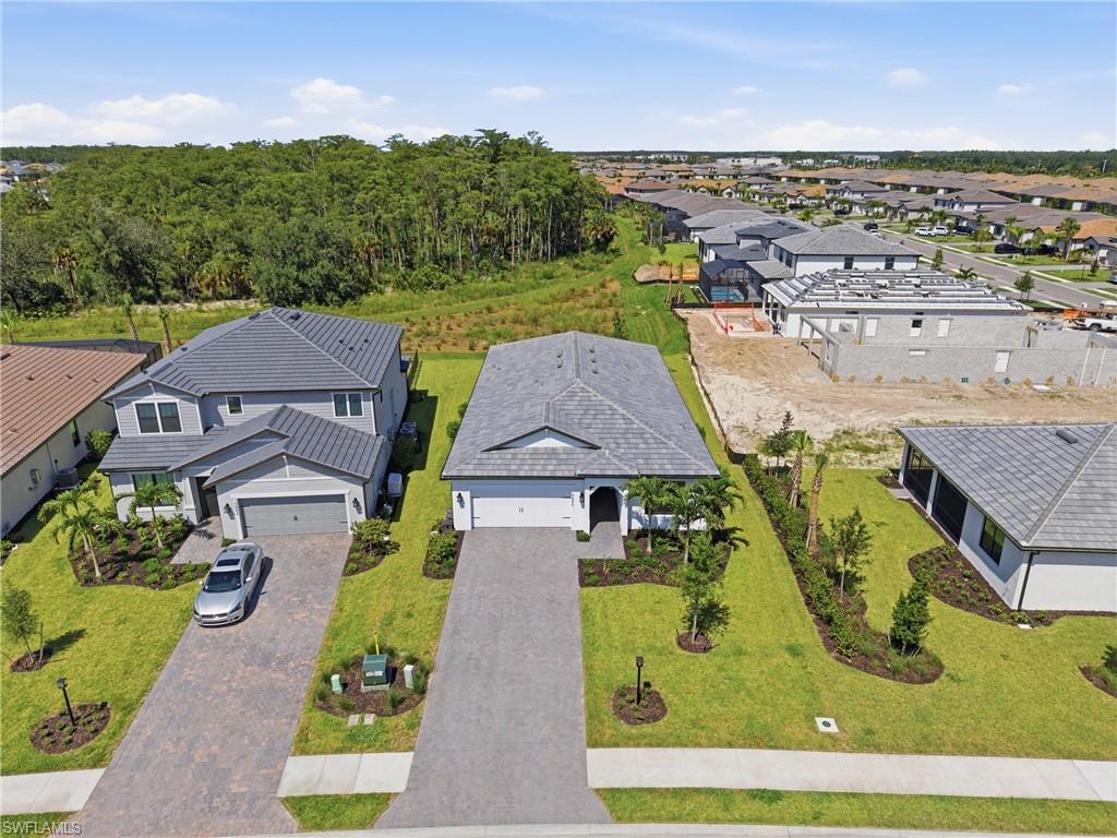 Single-story residence featuring a tile roof, paver driveway, and manicured landscaping