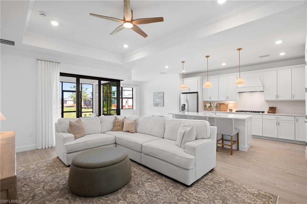Open concept living space featuring a tray ceiling, recessed lighting, and wood-finish flooring