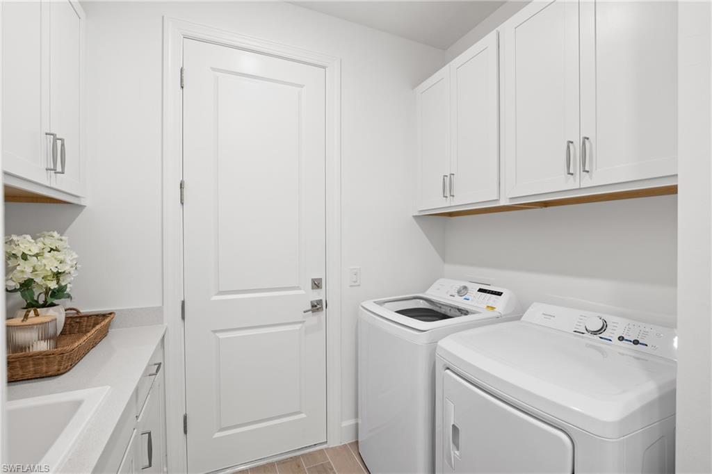 White shaker cabinetry, light-toned countertop, wood-finish flooring, and white paneled door