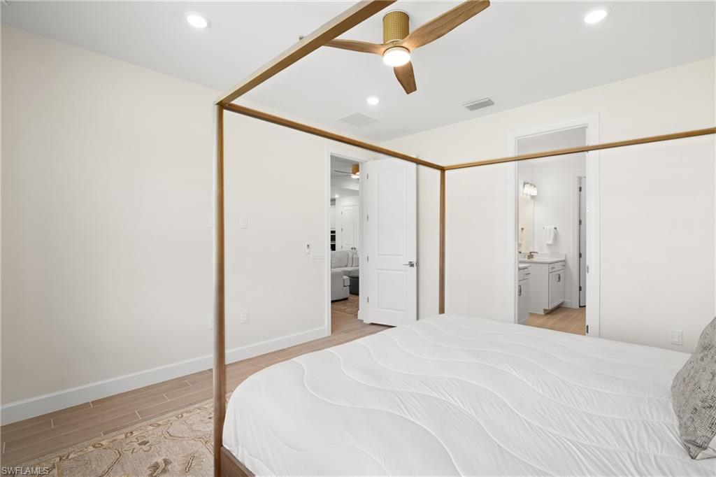 Recessed lighting, wood-finish ceiling fan, wood-finish flooring, white solid core doors, and a bathroom vanity with sconce lighting