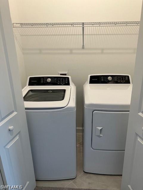 Clothes washing area featuring washing machine and dryer and light tile patterned flooring