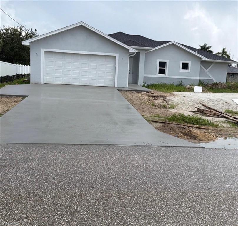 Newly constructed residence featuring a light gray stucco exterior, white trim, and a dark shingle roof