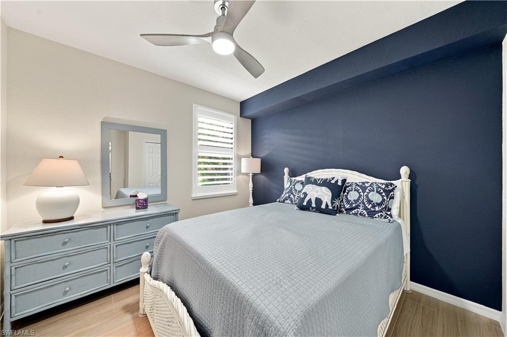 Wood-finish flooring, ceiling fan, white window shutters, and a blue accent wall