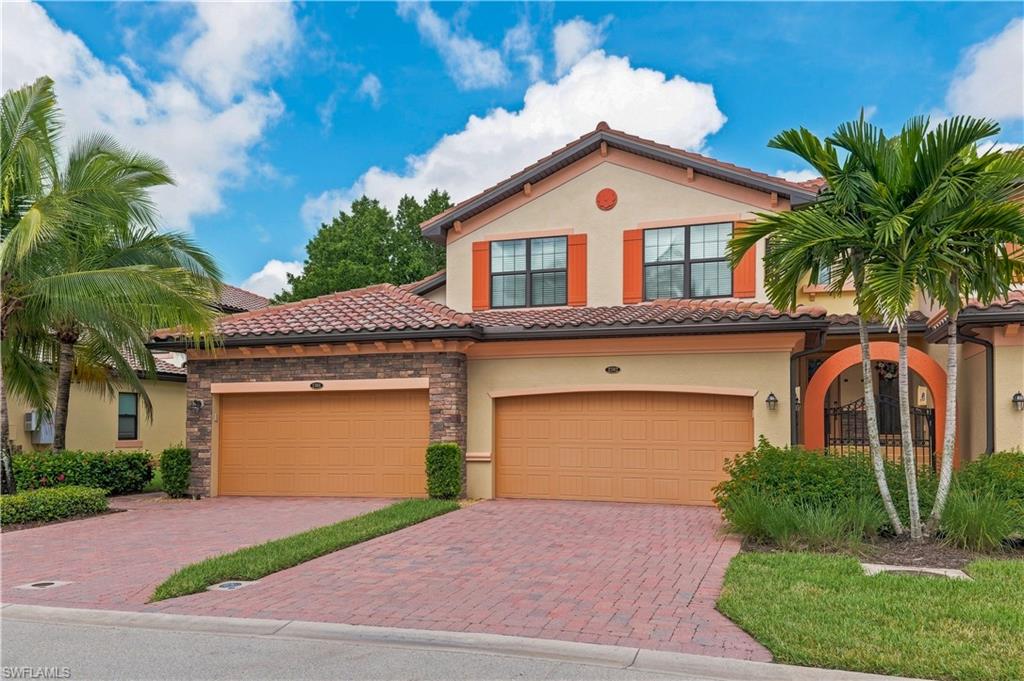 Mediterranean-inspired exterior with a tile roof, stucco finish, brick paver driveway, and two garage doors