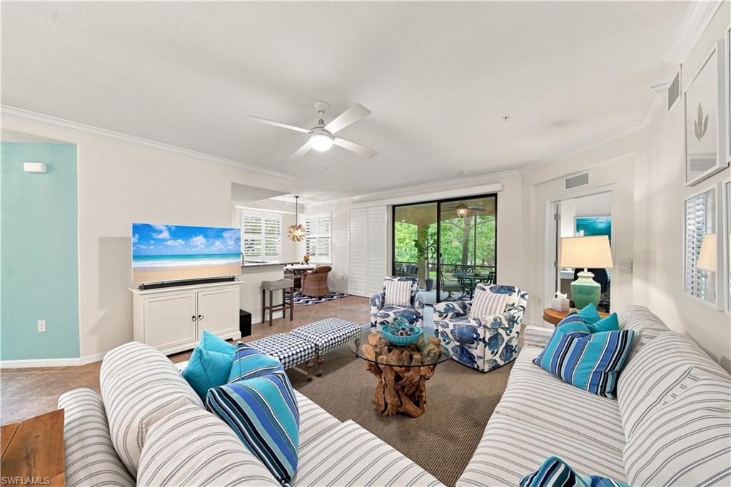 Open-concept living area with a ceiling fan, crown molding, and direct access to an enclosed outdoor space