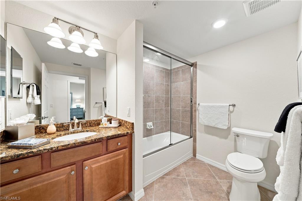 Vanity with a granite countertop, undermount sink, and wood-finish cabinetry