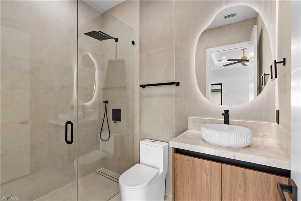 Bathroom featuring a glass-enclosed shower with a black rain showerhead, a floating wood-finish vanity with a vessel sink, and an illuminated irregular-shaped mirror