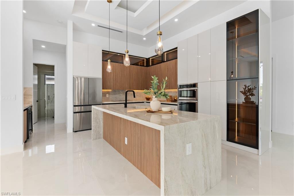 Gourmet kitchen featuring a large stone island, stainless steel appliances, wood-finish cabinetry, and recessed lighting