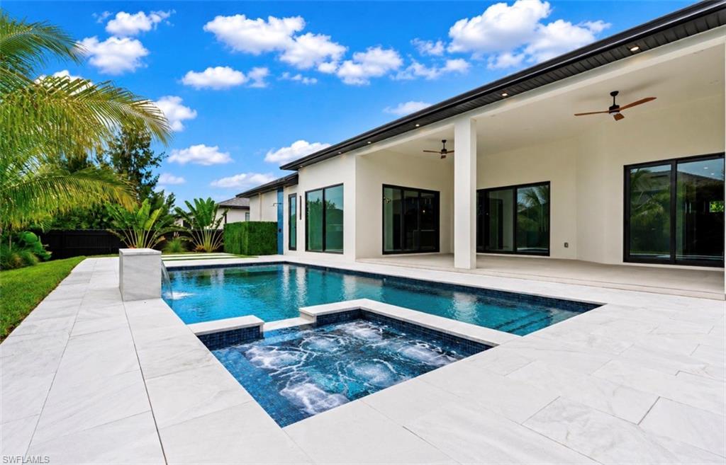 Expansive outdoor living area featuring a swimming pool, integrated spa, and spacious patio with large format tile
