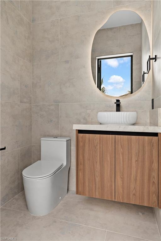 Floating wood-finish vanity with a vessel sink, integrated mirror lighting, and large format wall and floor tiling