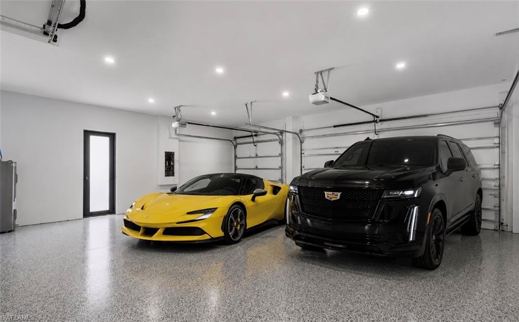 Spacious garage featuring a durable epoxy floor, recessed lighting, and three overhead garage doors