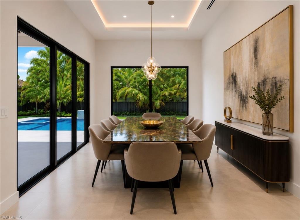 Recessed ceiling lighting, tray ceiling, full-height sliding glass doors, large window, and a built-in wall cabinet with a stone countertop