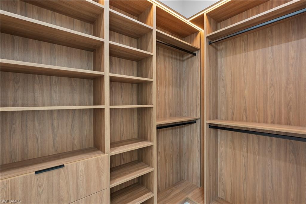 Built-in closet system featuring wood-finish shelving, integrated hanging rods, and a drawer with a matte black pull