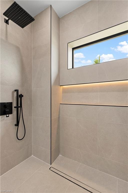 Contemporary shower with a matte black rain shower head, large format wall tiling, recessed linear window, integrated niche with accent lighting, and a linear floor drain