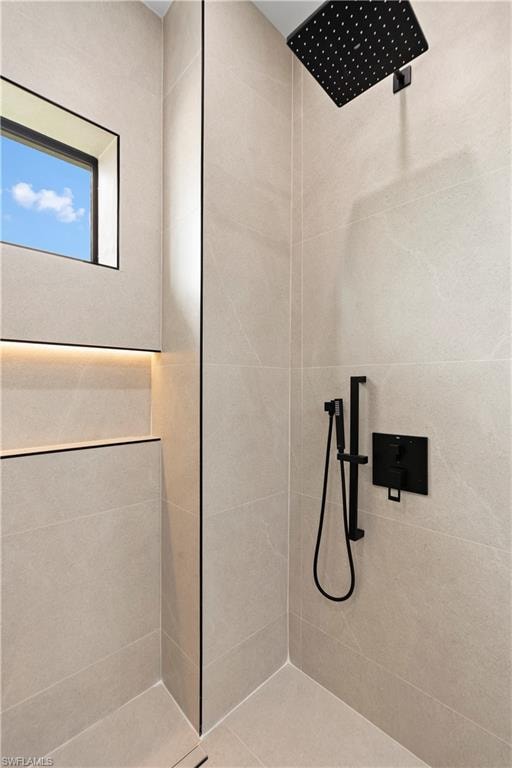 Tiled shower enclosure featuring a square window, integrated shelving with accent lighting, and matte black fixtures including a rainfall shower head and handheld sprayer