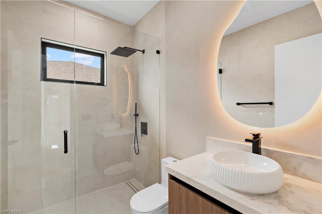 Glass-enclosed shower with a rainfall showerhead, linear drain, and transom window