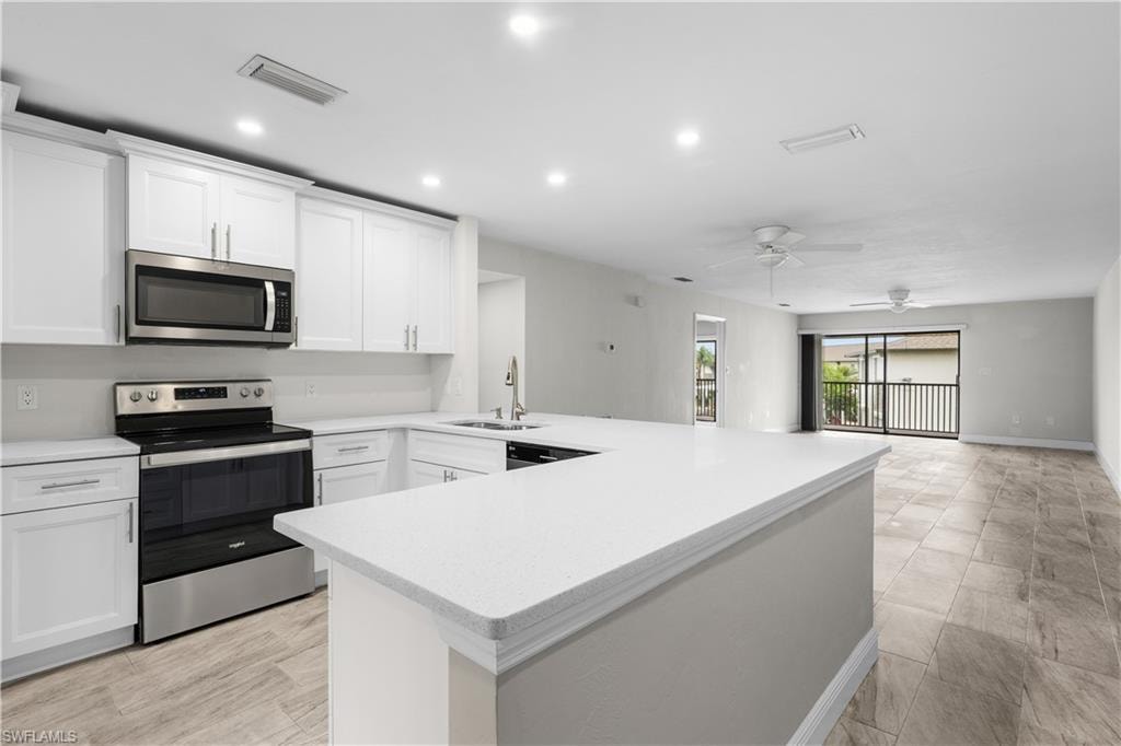 White shaker cabinetry, stainless steel appliances, white countertops, tile flooring, and sliding glass doors