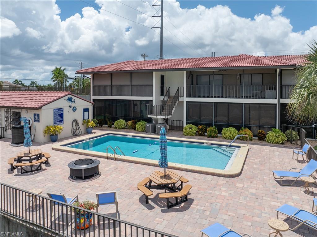 Rectangular swimming pool surrounded by a paver patio with a built-in fire pit