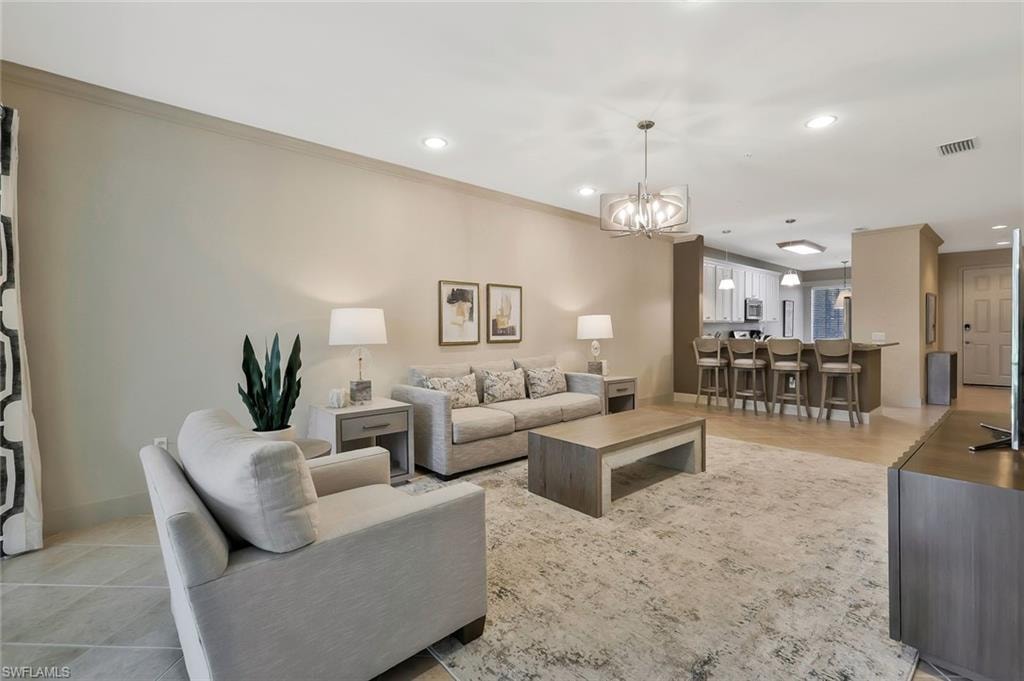 Living area featuring ornamental molding, visible vents, recessed lighting, and a notable chandelier