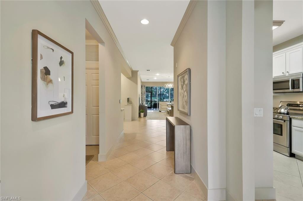 Corridor with ornamental molding, baseboards, recessed lighting, and light tile patterned flooring