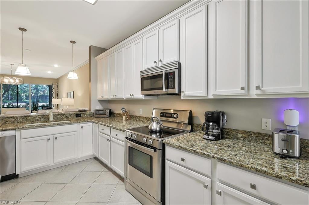 Kitchen with decorative light fixtures, a sink, white cabinetry, stainless steel appliances, and light tile patterned flooring