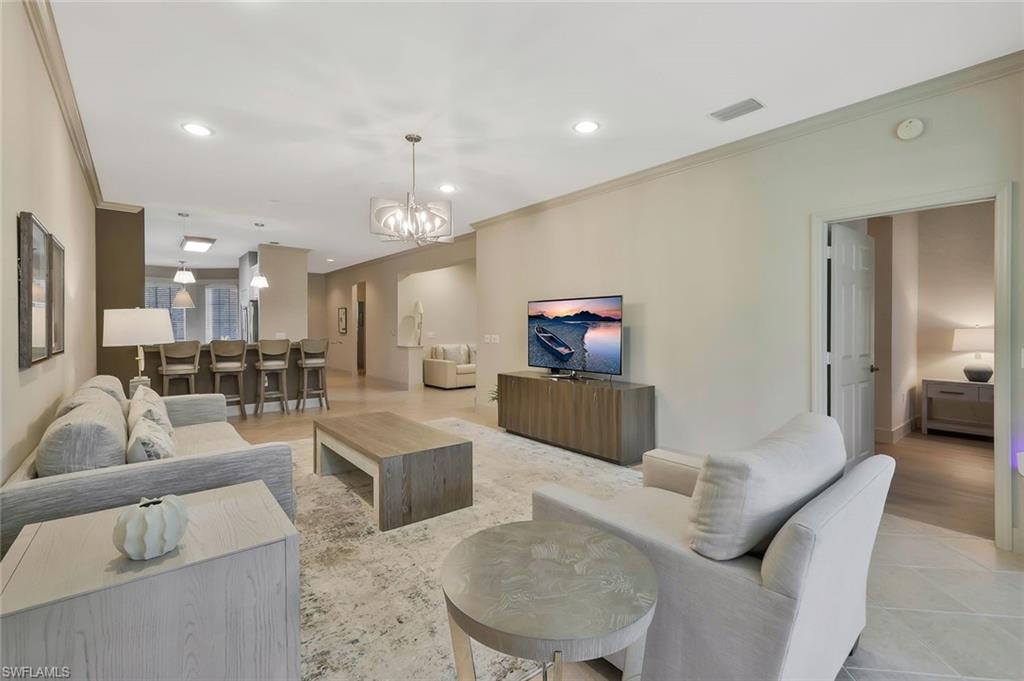 Living room featuring a chandelier, ornamental molding, visible vents, and recessed lighting
