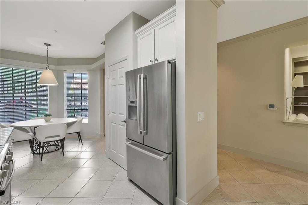 Kitchen featuring white cabinets, light tile patterned floors, pendant lighting, and appliances with stainless steel finishes