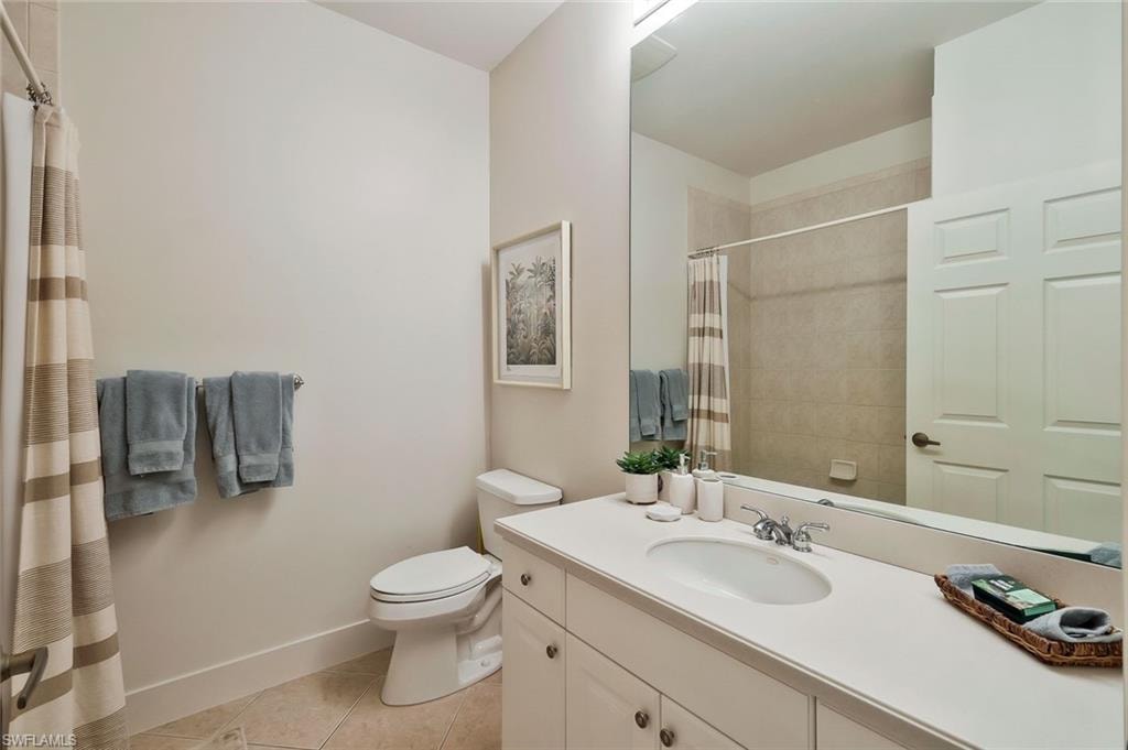 Full bathroom featuring vanity, toilet, curtained shower, tile patterned floors, and baseboards