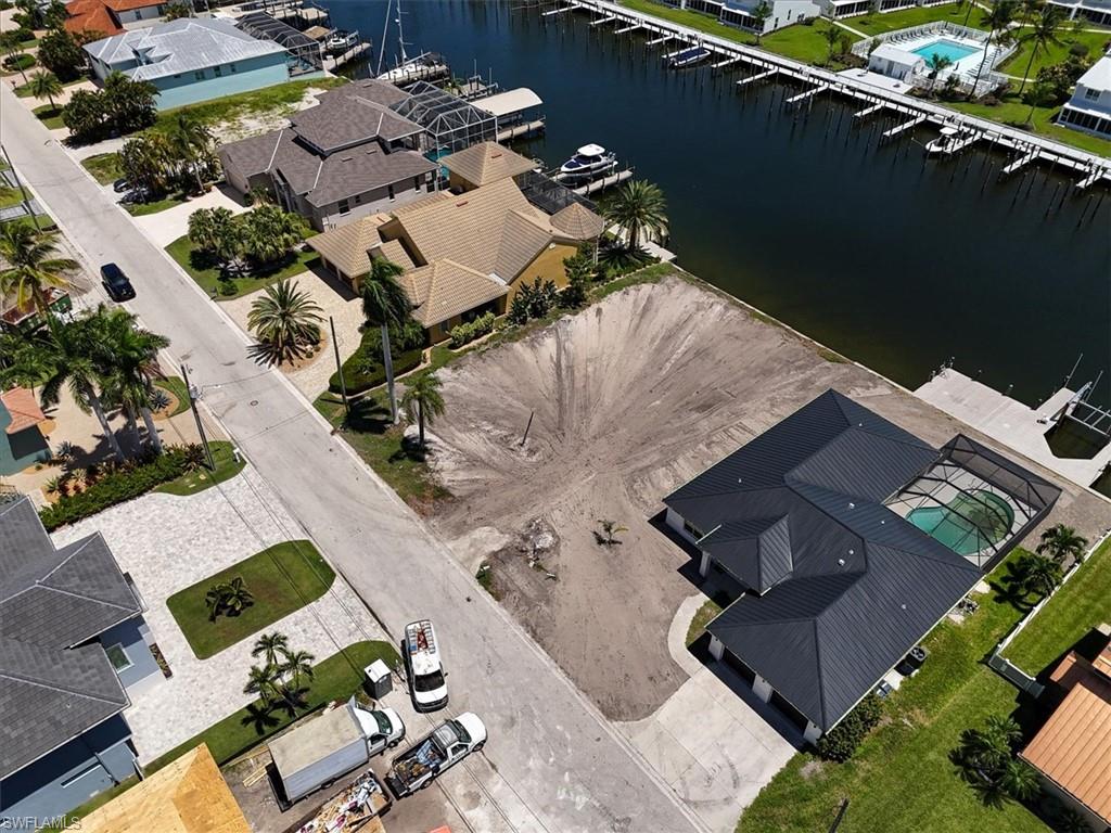 Waterfront property with private dock, a screened pool enclosure, paved driveway, and mature landscaping
