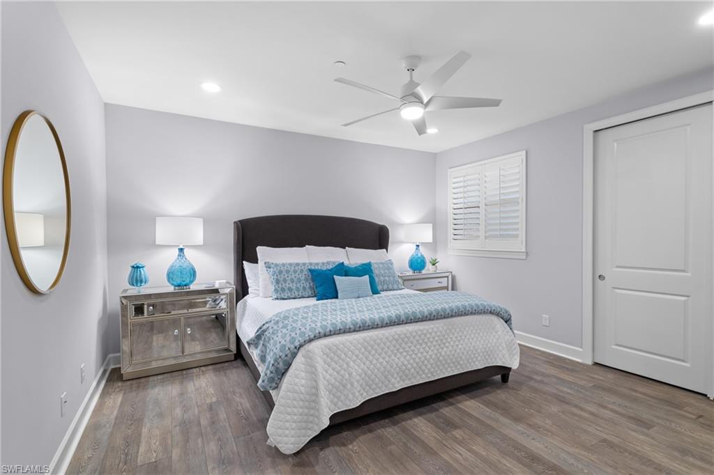 Wood-finish flooring, recessed lighting, ceiling fan, window with plantation shutters, and a paneled door