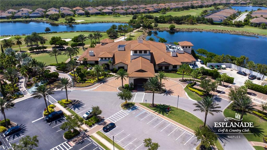 Clubhouse building with a multi-gabled tile roof, surrounded by mature palm trees and lush landscaping