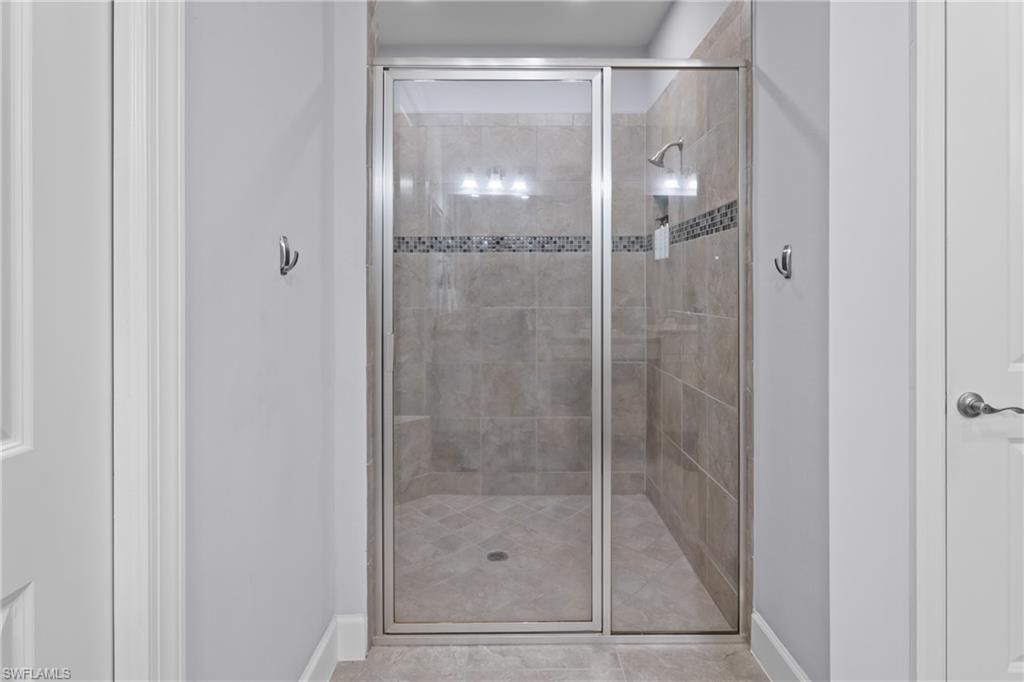 Frameless glass shower enclosure with a tiled interior, featuring a mosaic tile accent band