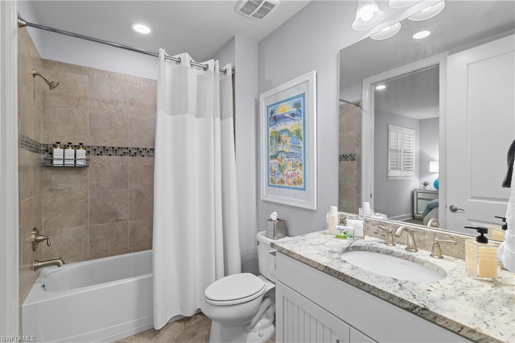 Bathroom featuring a single vanity with stone countertop, undermount sink, and brushed nickel fixtures