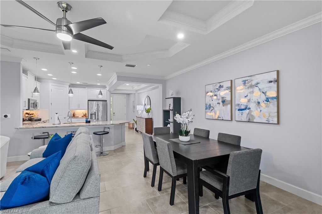 Open-concept living space with tray ceilings, recessed lighting, and tile flooring