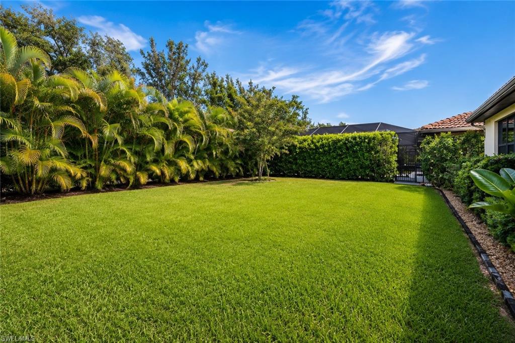 Expansive grassy lawn with established perimeter landscaping and mature trees