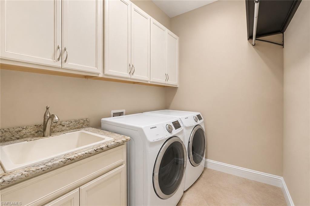 Utility room featuring upper cabinetry, a utility sink with a stone-finish countertop, and a built-in hanging rod