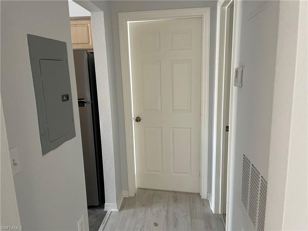 Hallway featuring electric panel and light hardwood / wood-style flooring