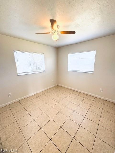 Neutral-toned interior with ceramic tile flooring, two windows, and a ceiling fan with integrated lighting